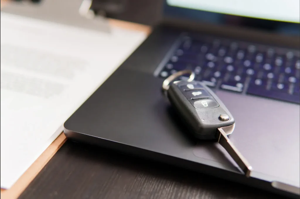 Kľúče od auta položené na notebooku vedľa firemných dokumentov – webinár o autách v spoločnosti z pohľadu zákona o dani z príjmov