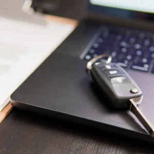 Kľúče od auta položené na notebooku vedľa firemných dokumentov – webinár o autách v spoločnosti z pohľadu zákona o dani z príjmov